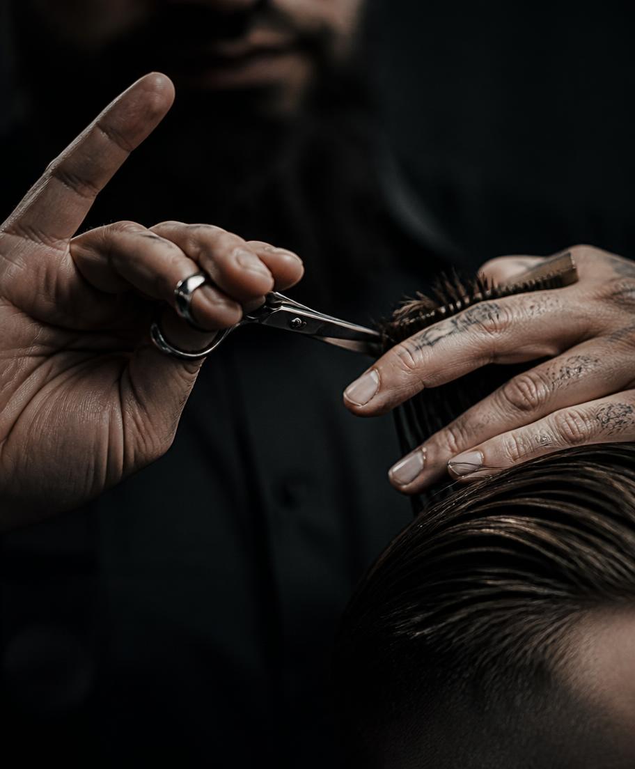 A barber cutting hair with scissors under low light